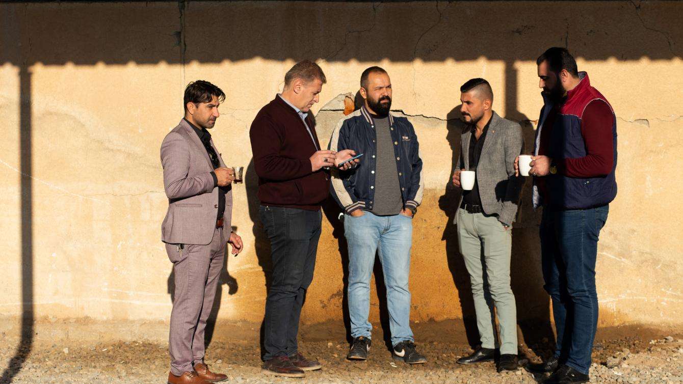 Men standing around together outside with their coffees