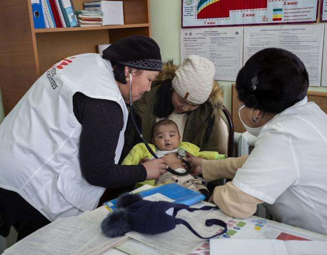 MSF staff attend to a smiling baby.