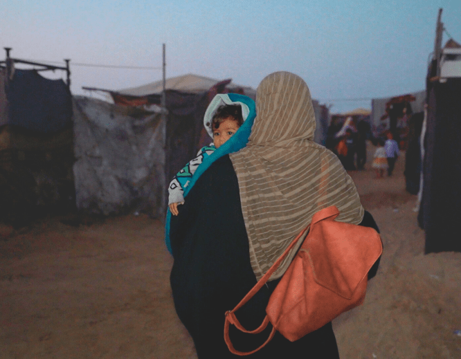 A displaced Palestinian woman and her child in a tented camp in Gaza.