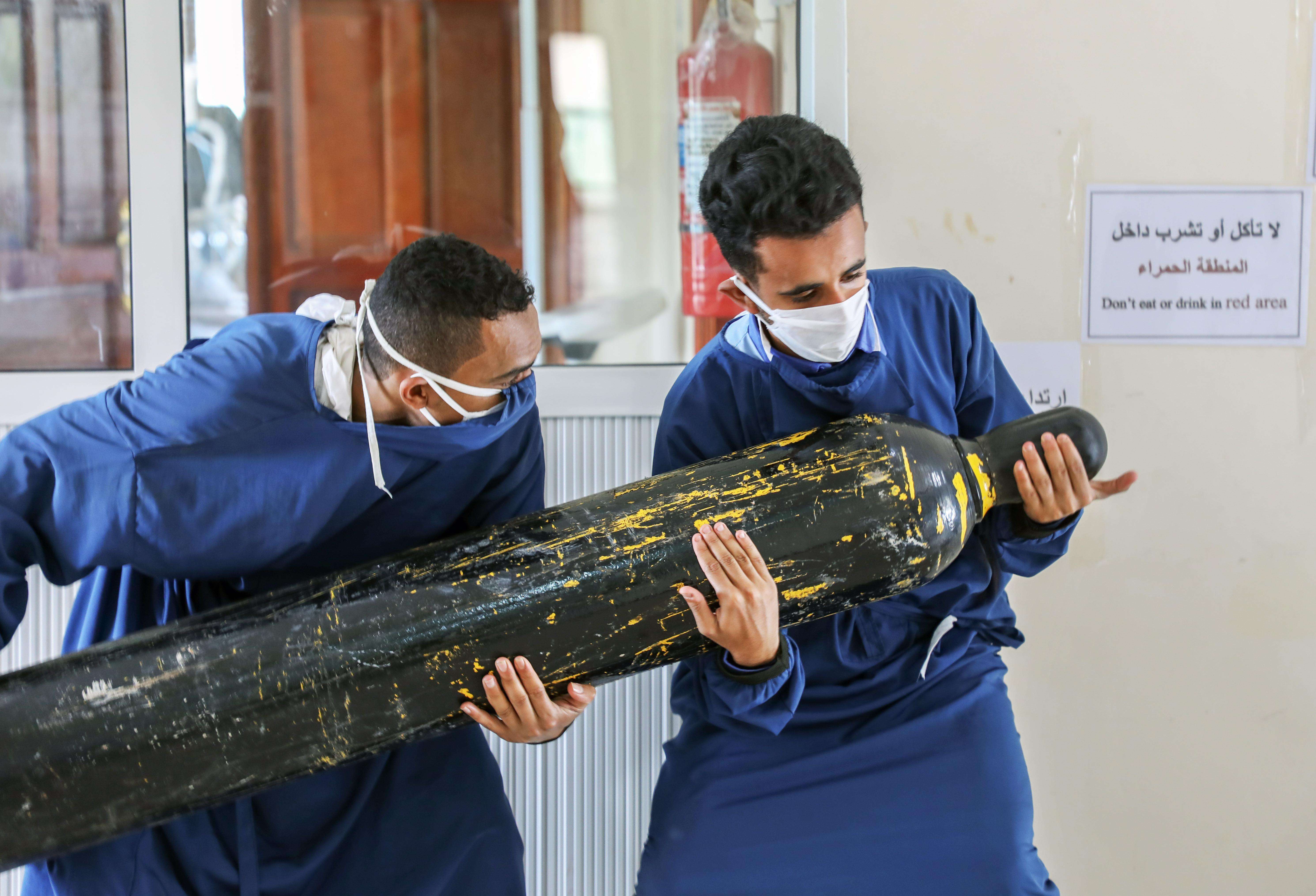 Workers carry an oxygen cylinder to the intensive care unit.