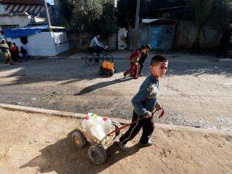 A Palestinian child fetches water from a distribution point in Rafah, Gaza.