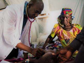 A physician providing care to a sick child at MSF's temporary hospital at Dungass, in the Magaria area