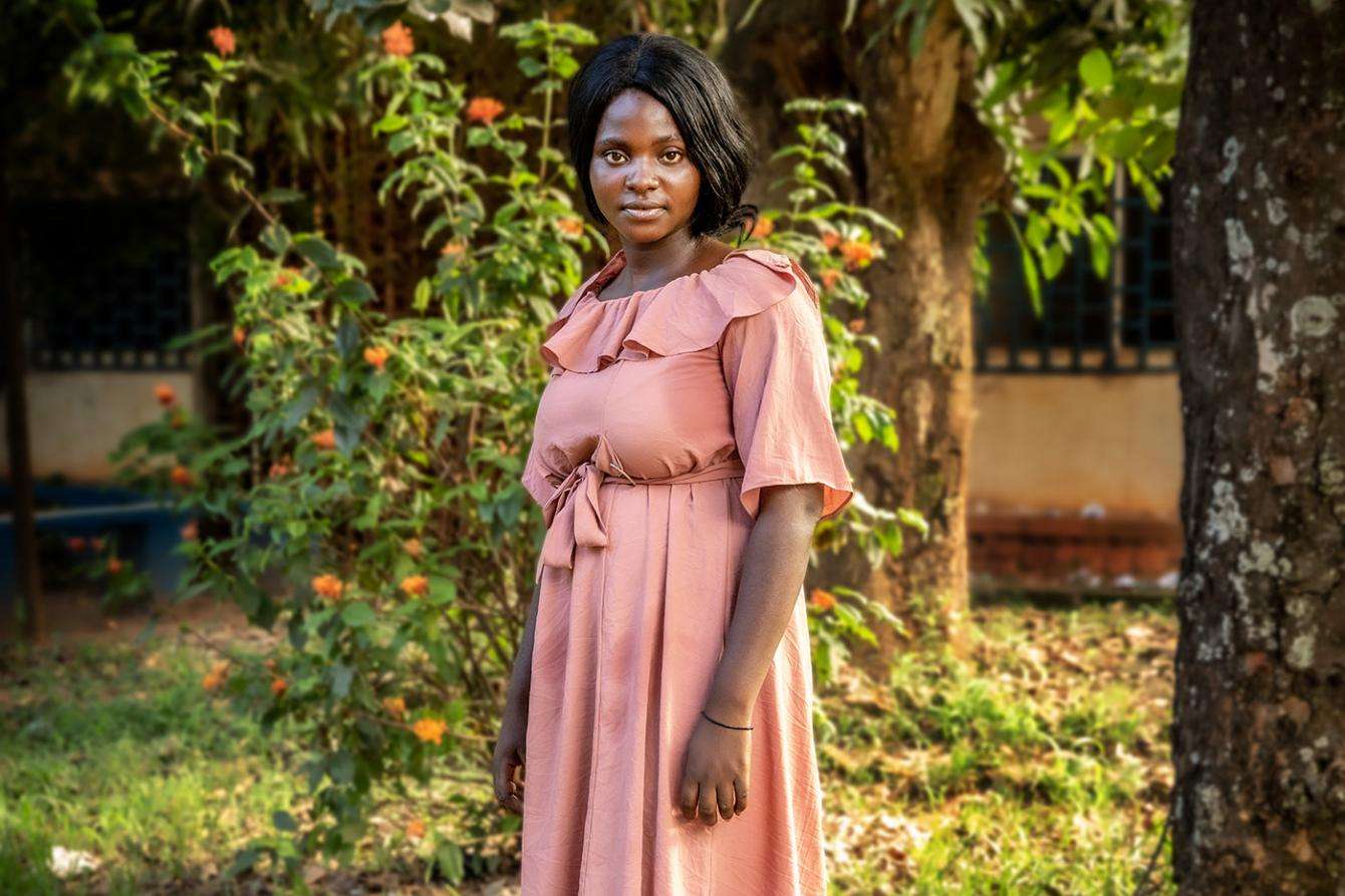 young woman in pink dress standing under trees