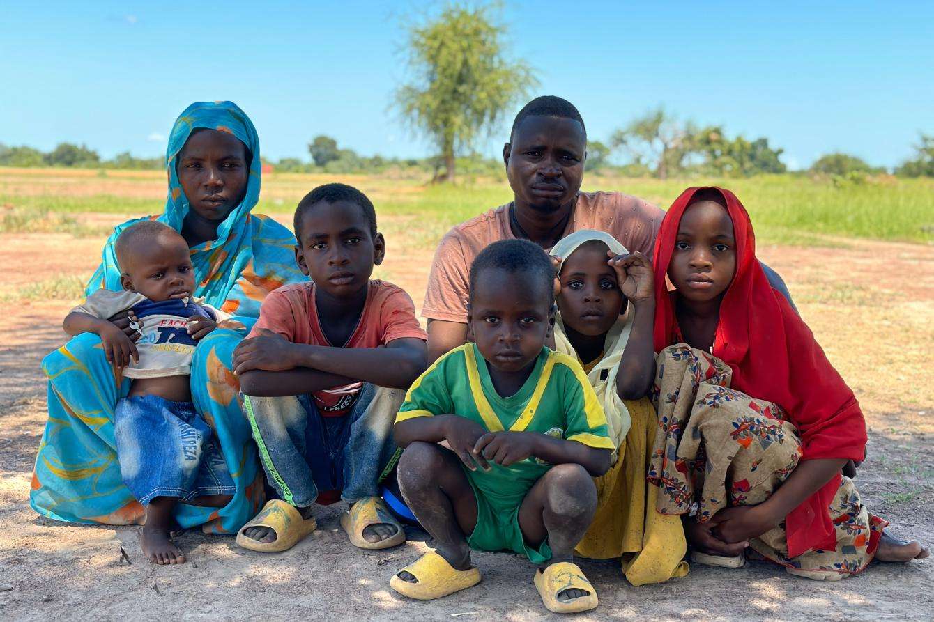 A refugee family from Sudan sits on the grass outside Wedweil camp in South Sudan.