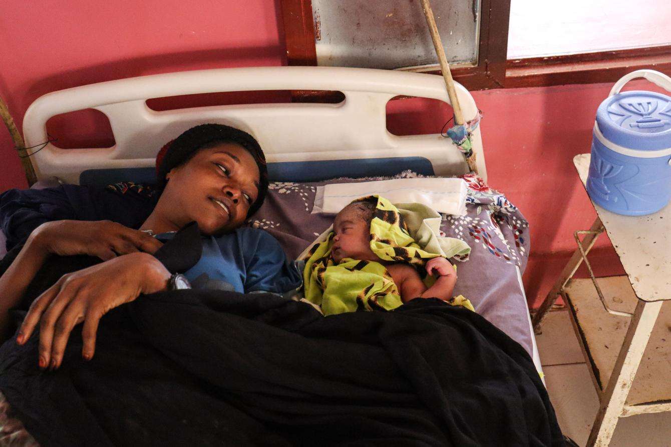 A woman with her baby in a hospital bed in South Darfur, Sudan.