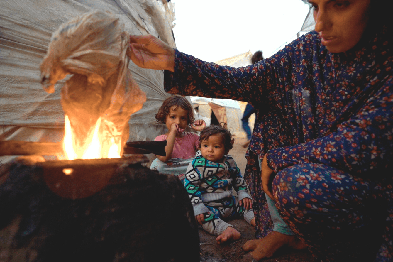 A displaced Palestinian family lights a fire in Gaza.