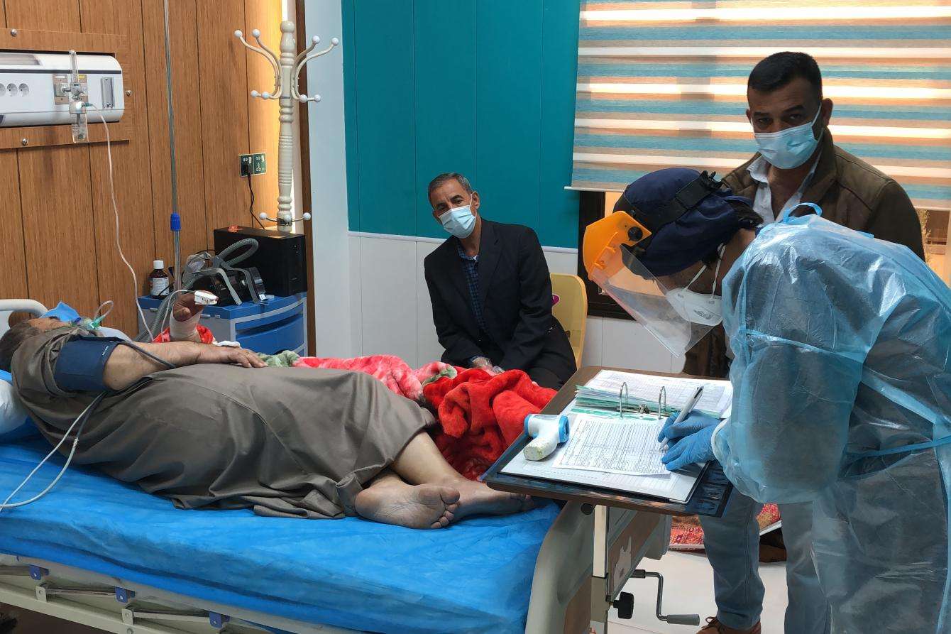 A nurse looks after a patient with loved ones in the room. 