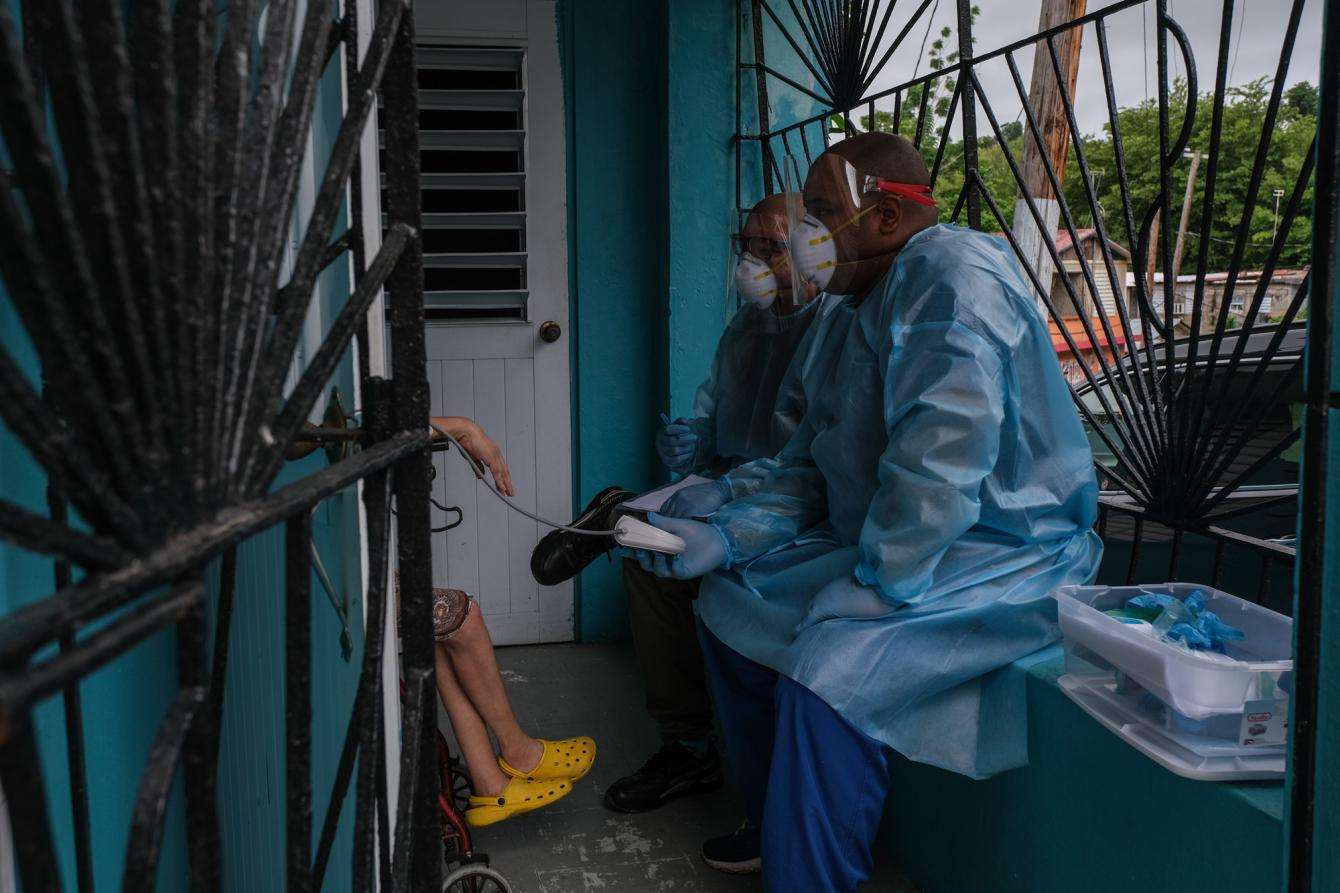 MSF physician Dr. Jonathan Caldera evaluates a patient while MSF nurse Omar Martinez takes her blood pressure reading during an in-home medical consultation in the community Buen Consejo in Rio Piedras, Puerto Rico.