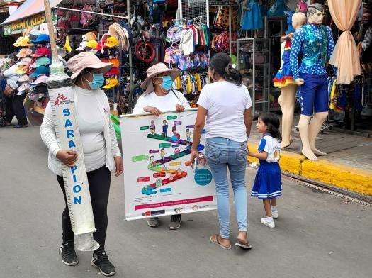 Members of MSF's health promotion team speak with a mother and child on the street in Peru.