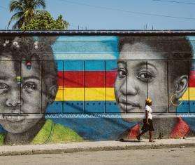 A woman walks past a mural in Bois-Verna, a residential area of Port-au-Prince.