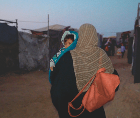 A displaced Palestinian woman and her child in a tented camp in Gaza.